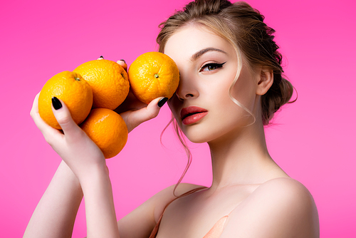 elegant beautiful blonde woman holding ripe oranges isolated on pink