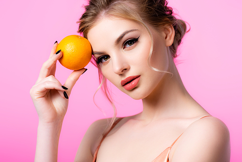 elegant beautiful blonde woman holding ripe orange isolated on pink