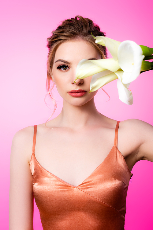 elegant beautiful blonde woman holding calla flowers in front of face isolated on pink