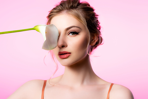 elegant beautiful blonde woman holding calla flower near face isolated on pink