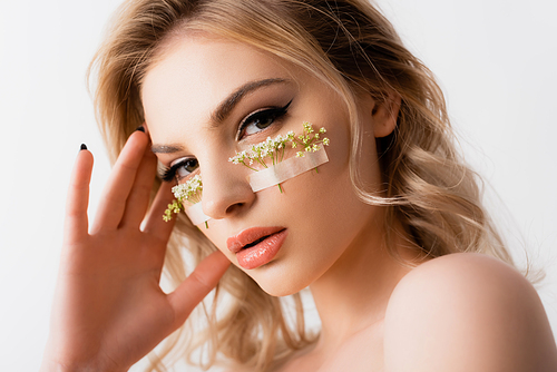 naked beautiful blonde woman with wildflowers under eyes isolated on white