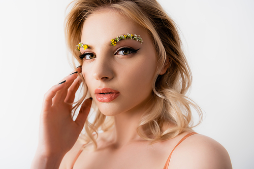 beautiful blonde woman with wildflowers on eyebrows touching face isolated on white