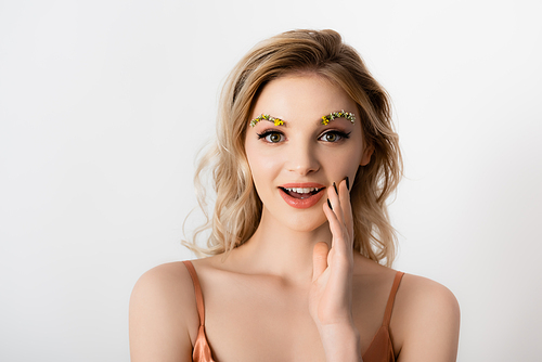 surprised beautiful blonde woman with wildflowers on eyebrows isolated on white