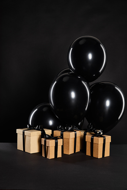 bunch of black balloons and gift boxes isolated on black, black Friday concept