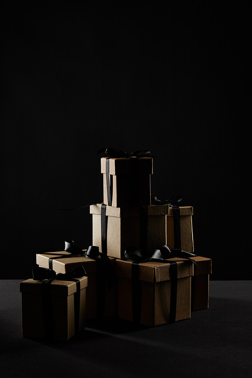cardboard gift boxes with black ribbons in darkness isolated on black, black Friday concept