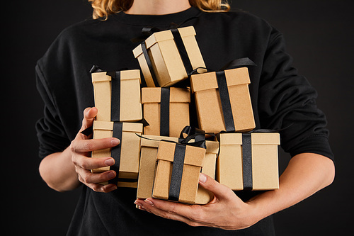 cropped view of woman holding cardboard gift boxes with ribbons isolated on black, black Friday concept