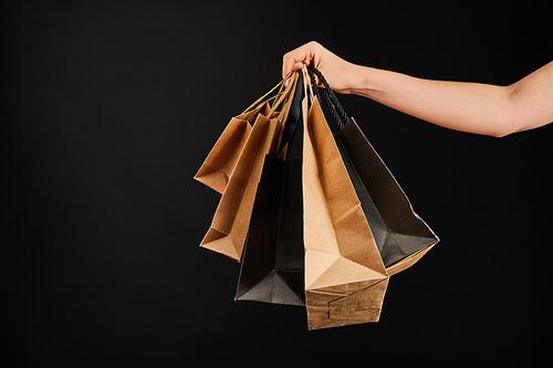 partial view of woman holding paper shopping bags isolated on black, black Friday concept