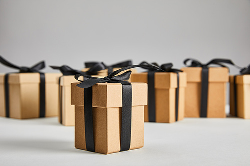 selective focus of cardboard gift box with black ribbon isolated on grey, black Friday concept