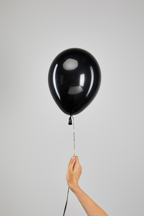 cropped view of woman holding  black balloon isolated on grey, black Friday concept
