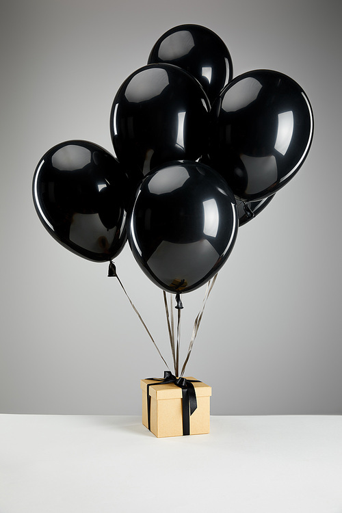 bunch of black balloons with gift box isolated on grey, black Friday concept
