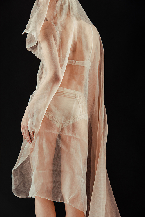Cropped view of girl in beige underwear and chiffon cloth isolated on black