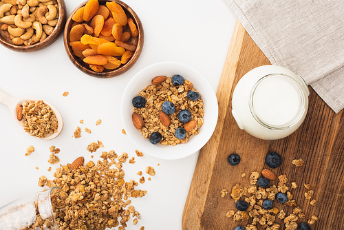 top view of delicious granola with yogurt, nuts, blueberry and dried apricots isolated on white