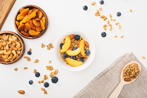 top view of delicious granola with nuts, peach, blueberry and dried apricots isolated on white