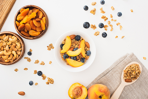 top view of delicious granola with nuts, peach, blueberry and dried apricots isolated on white