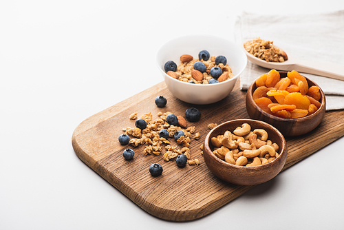 delicious granola with nuts,dried apricots and blueberry on wooden board on white background