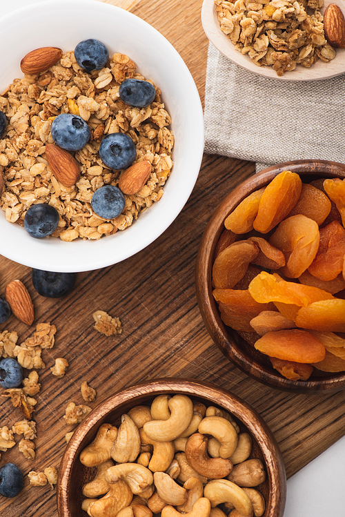 top view of delicious granola with nuts, blueberry and dried apricots on wooden board