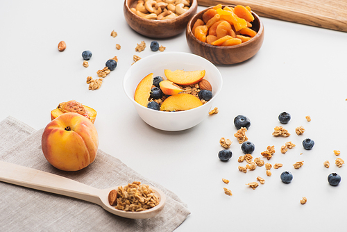 delicious granola with nuts, peach, blueberry and dried apricots on white