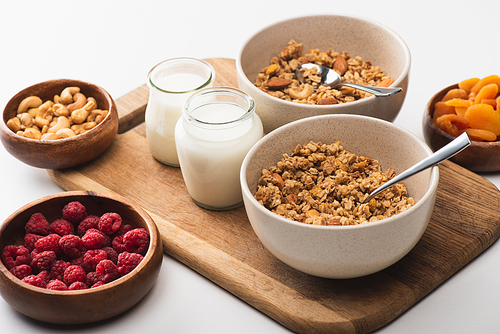 delicious granola with nuts, fruits and yogurt on wooden board on white background