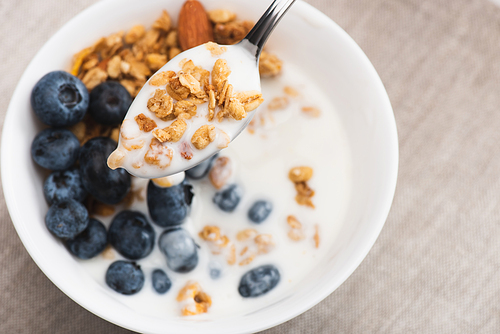 spoon with delicious granola and yogurt on blurred background