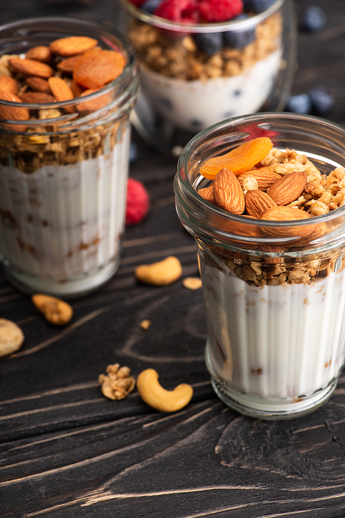 delicious granola with dried apricots, nuts and yogurt in glass cup on blurred background