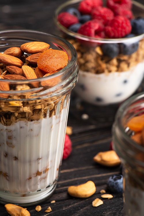 closeup of delicious granola with dried apricots, nuts and yogurt in glass cup on blurred background