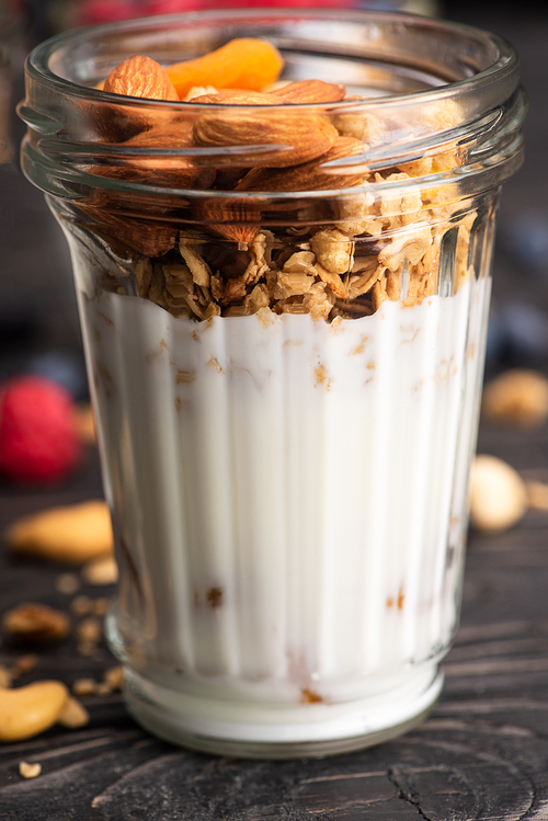 closeup of delicious granola with dried apricots, nuts and yogurt in glass cup