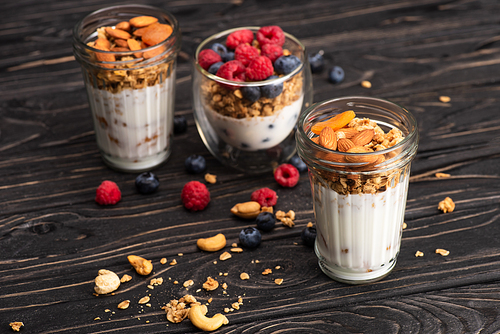 delicious granola with dried apricots, nuts and yogurt in glass cups on wooden surface on blurred background