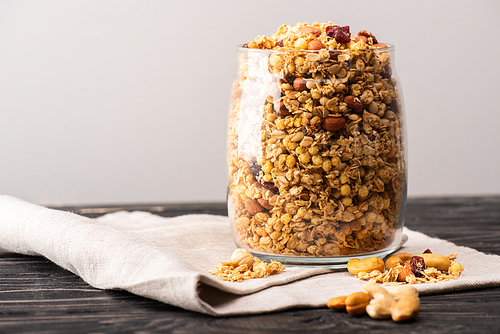 delicious granola in glass gar on napkin isolated on grey