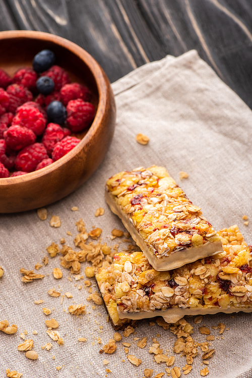 delicious muesli bars on napkin with blurred berries