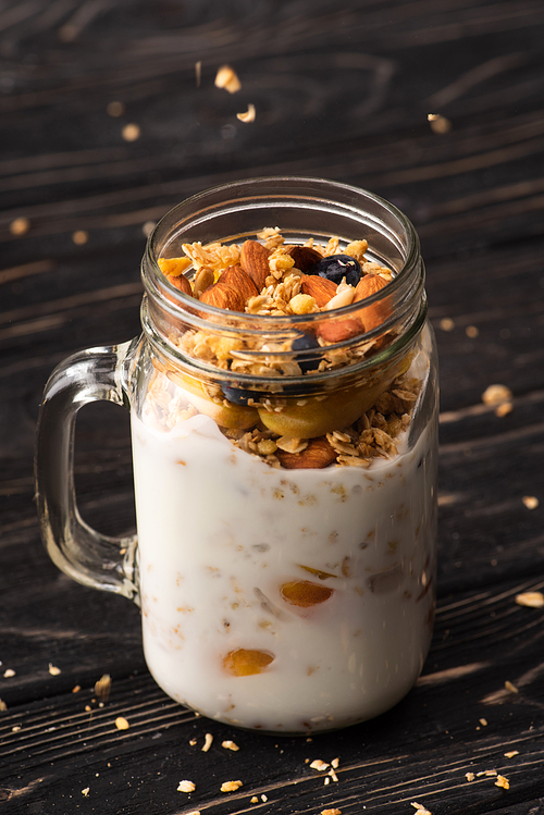 delicious granola with yogurt, nuts, peach, blueberry in glass jar