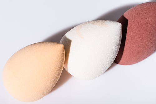 close up view of makeup sponges on white background