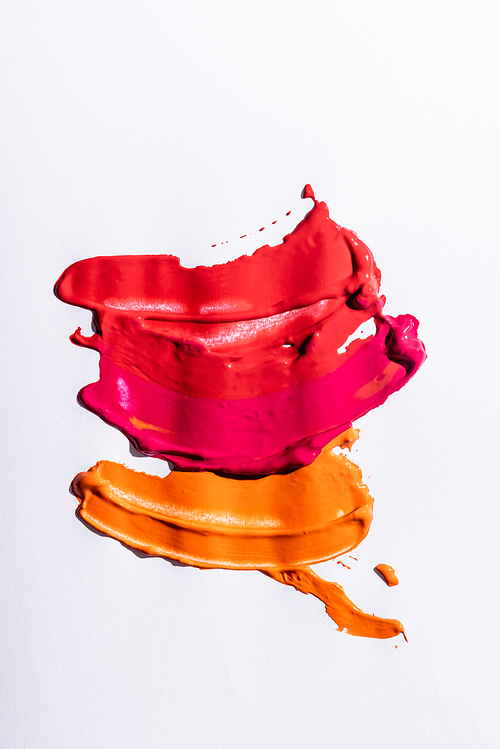 top view of red, orange and pink abstract brushstrokes on white background
