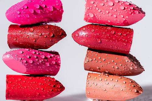 stack of wet colorful lipsticks on white background