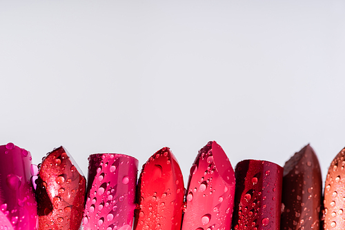 close up view of wet lipsticks in row isolated on white
