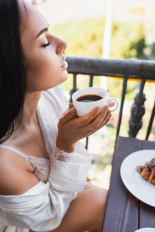beautiful brunette woman enjoying drinking coffee with closed eyes