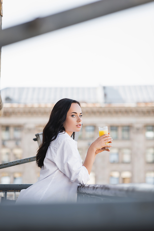 side view of brunette woman drinking orange juice