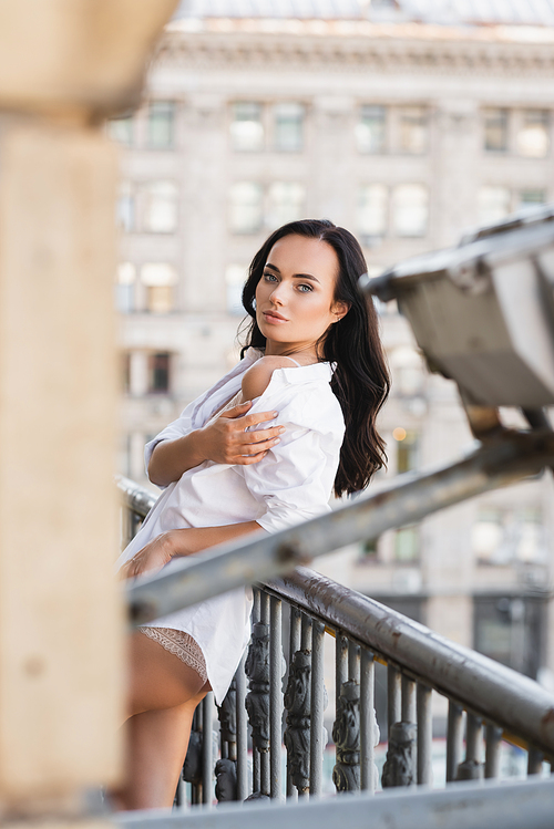 woman in white shirt posing on balcony and showing bare shoulder