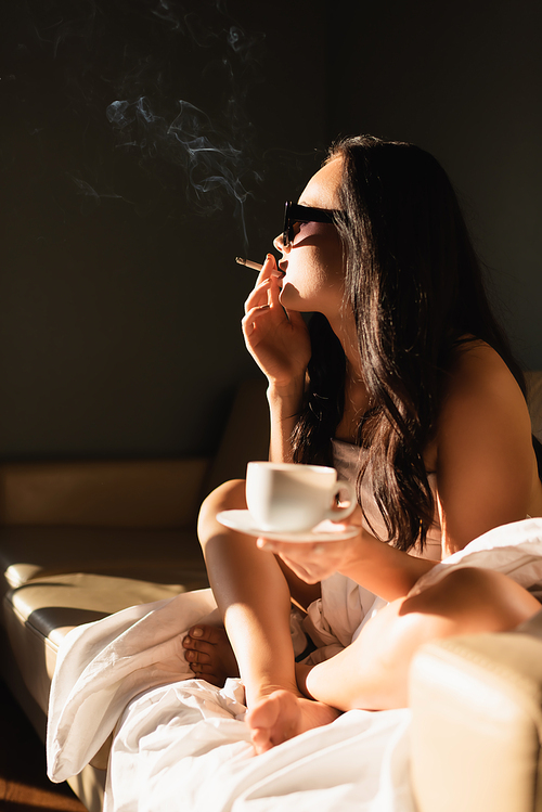 sexy brunette woman covered in white sheet smoking cigarette and drinking coffee