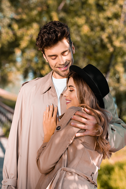 유토이미지 | man in trench coat hugging woman in hat outside
