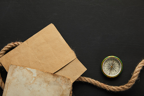 top view of vintage paper, rope, compass on black background