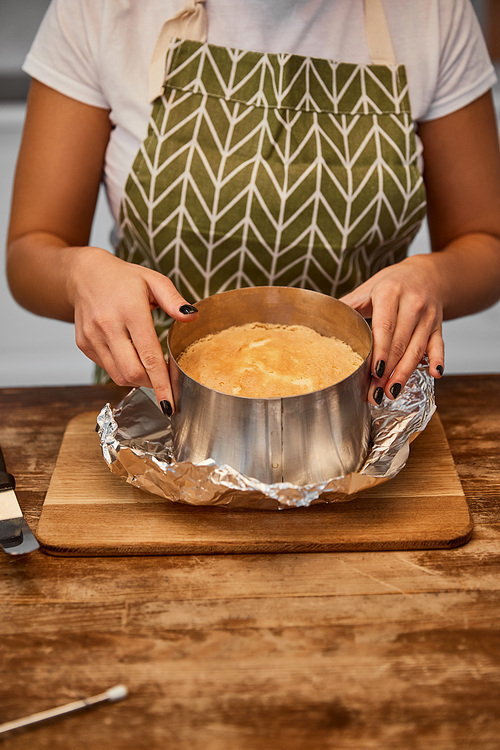 Cropped view of confectioner doing form of cake on chopping board