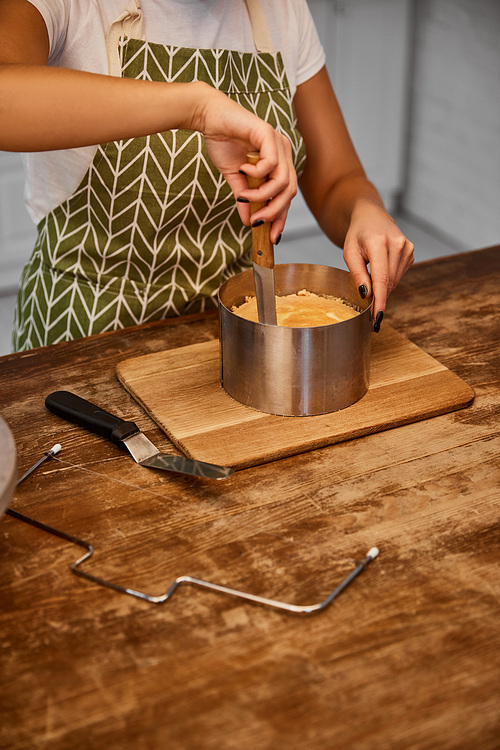 Partial view of confectioner cutting cake with knife