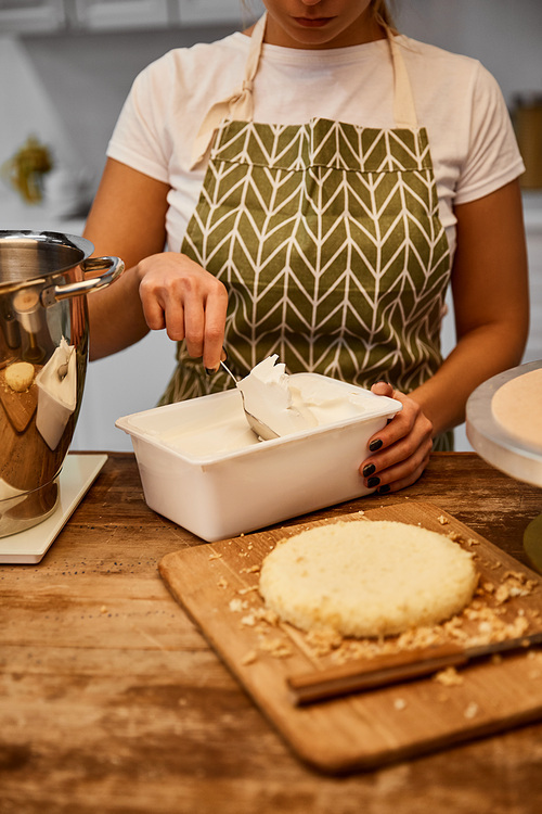 Confectioner taking cream for cooking cake in kitchen