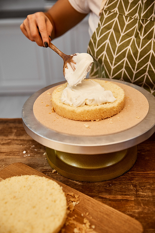 Partial view of confectioner spreading cream on cake layer