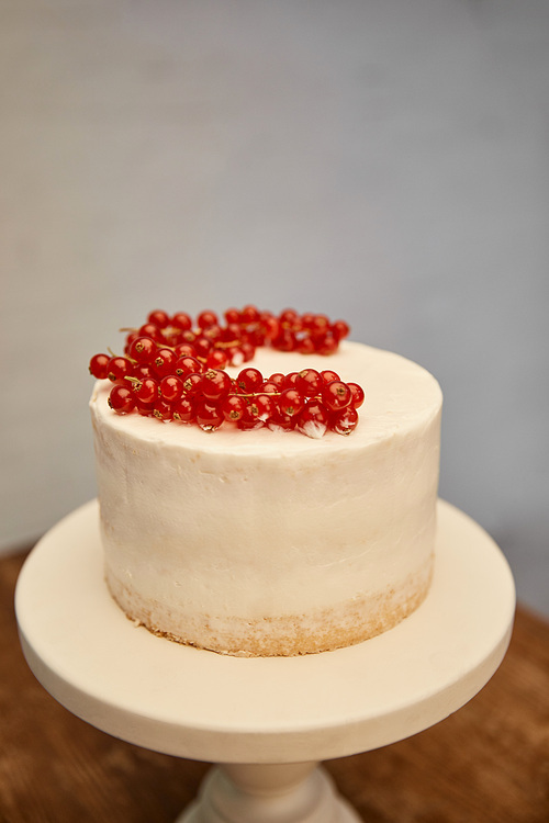 Tasty sponge cake with cream and fresh redcurrant on cake stand