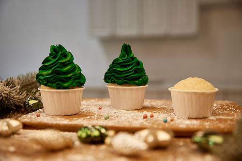 Selective focus of tasty cupcakes with christmas balls and spruce branch on table