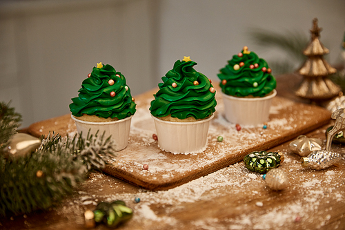 Tasty cupcakes with christmas balls and spruce branch on table
