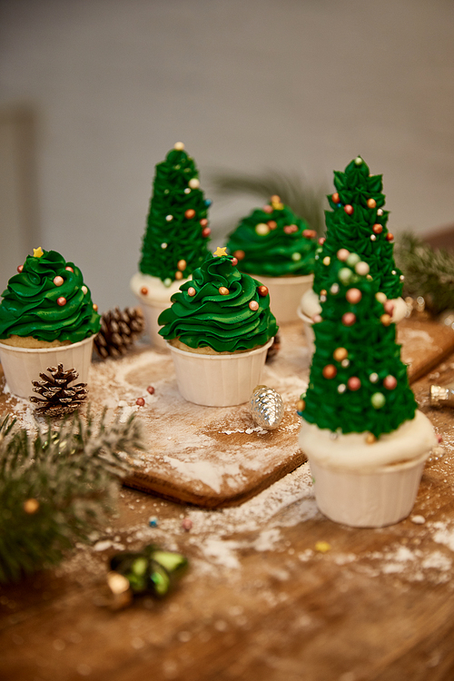 Decorated Christmas tree cupcakes with christmas balls with spruce branch and cones on table
