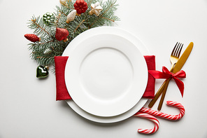top view of festive Christmas table setting on white background with decoration, pine branch and candies