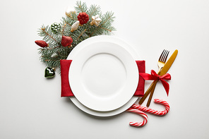 top view of festive Christmas table setting on white background with decoration, pine branch and candies